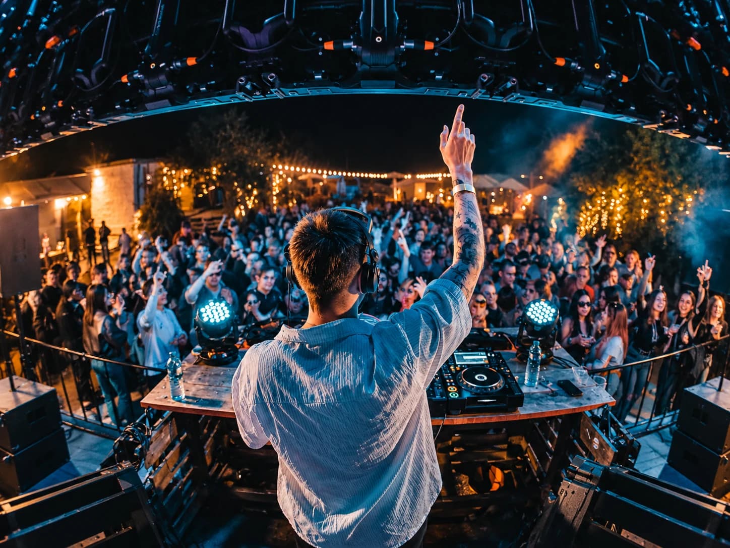 DJ on stage facing the crowd at a night-time open-air event