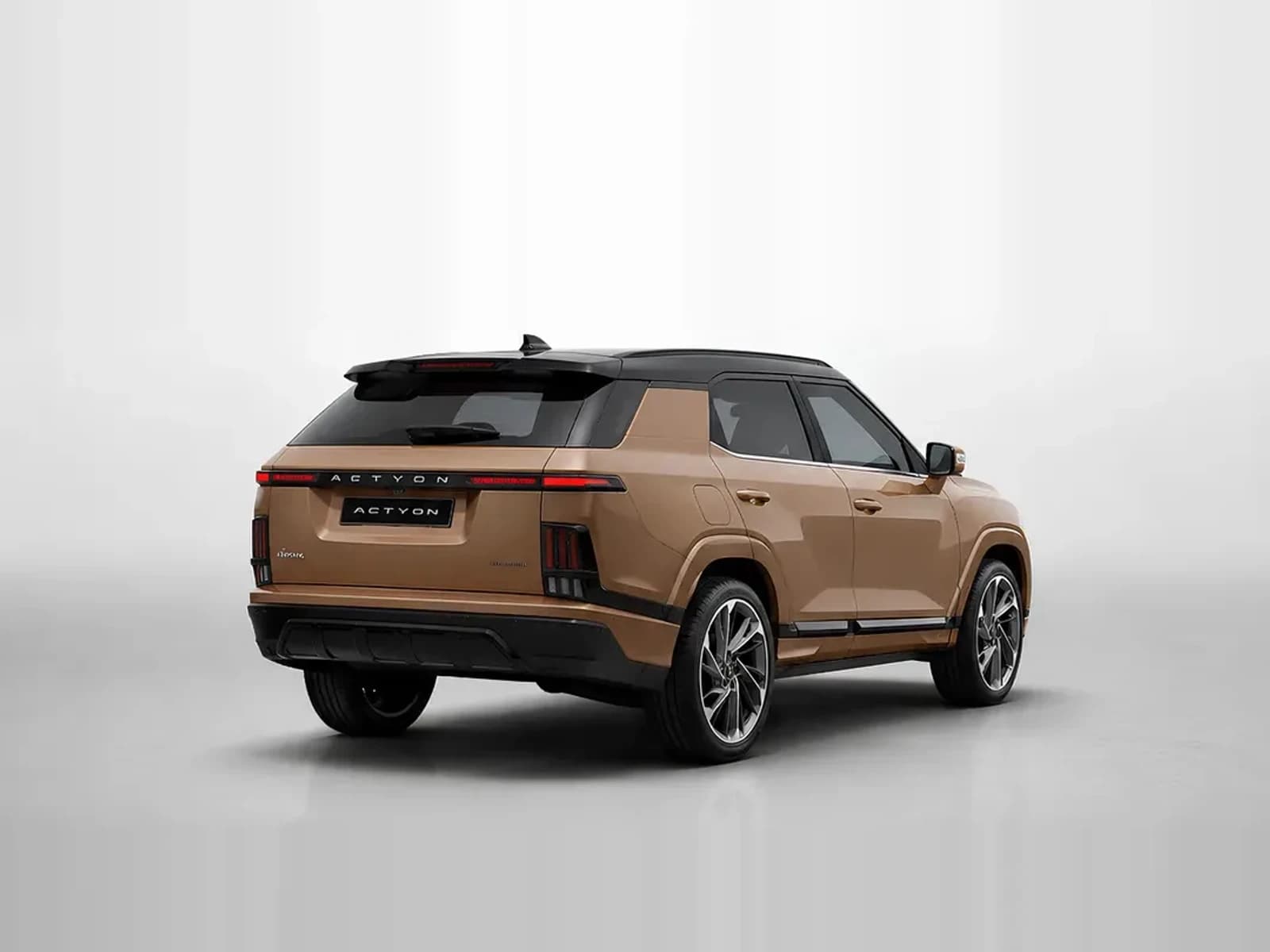 Bronze KGM Actyon SUV seen from the rear on a studio backdrop